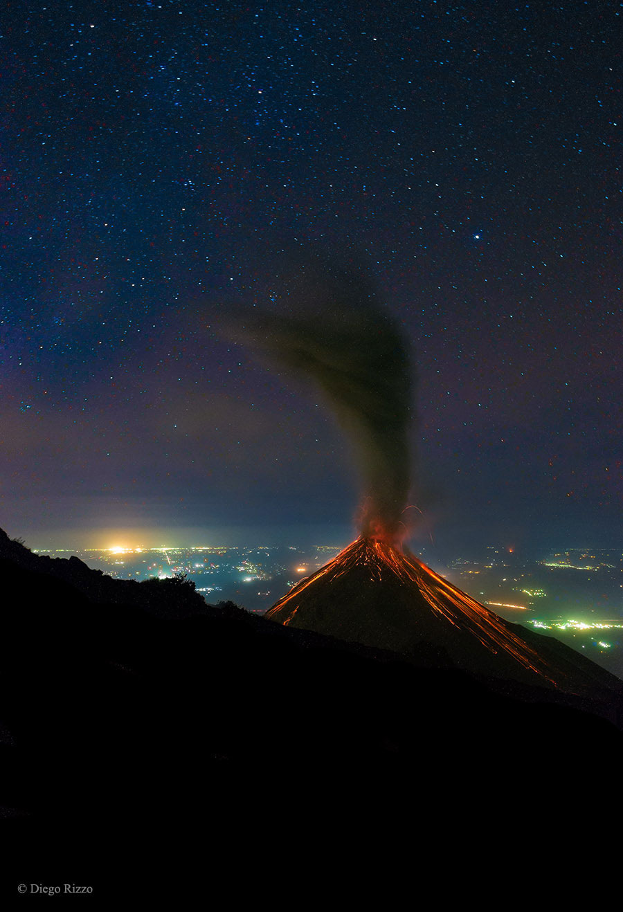 Volcán de lume en erupción baixo as estrelas