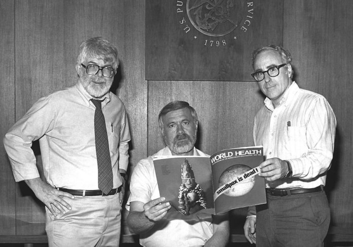 Donald Millar (esquerda), Willliam Foege (centro) e Michael Lane (dereita), impuslores do programa de erradicación da varíola, posan coa portada da revista Global Health que anuncia a erradicación da enfermidade en 1980. Foto: Biblioteca do CDC.