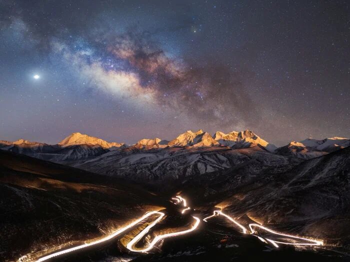 O ceo estrelado sobre a carretera nacional máis alta do mundo (Yang Sutie): A Estrada Nacional 219, no Tíbet, brilla en primeiro plano coa luz dos autos que circulan a toda velocidade polas súas curvas serpenteantes, a serena variedade de estrelas no disco da Vía Láctea brillando no alto, fotografada cun instrumento separado.
