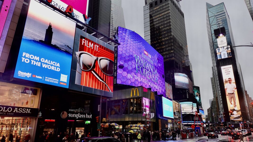 Á esquerda, foto da Torre de Hércules no anuncio proxectado en Times Square. Crédito: Clínica Dental Pardiñas